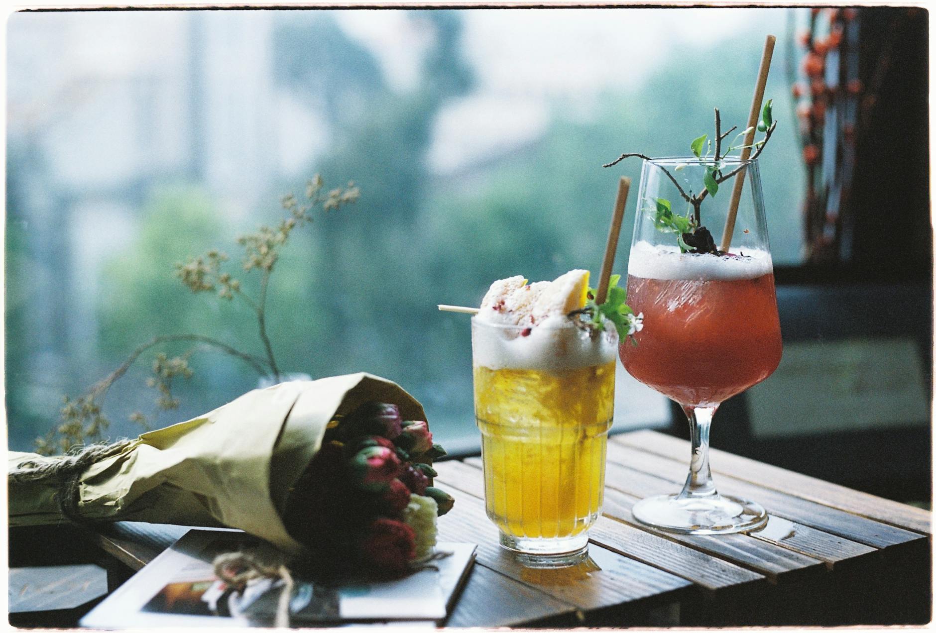 Dwa kolorowe koktajle przy oknie na rustykalnym drewnianym stole