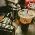 Dwie szklanki kawy mrożonej ze słomkami obok starego aparatu na stole