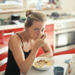 Kobieta jedząca owsiankę z mlekiem przy stole w kuchni