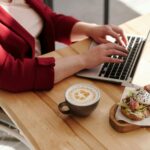 Kobieta na wózku przy stole z laptopem, kawą i śniadaniem