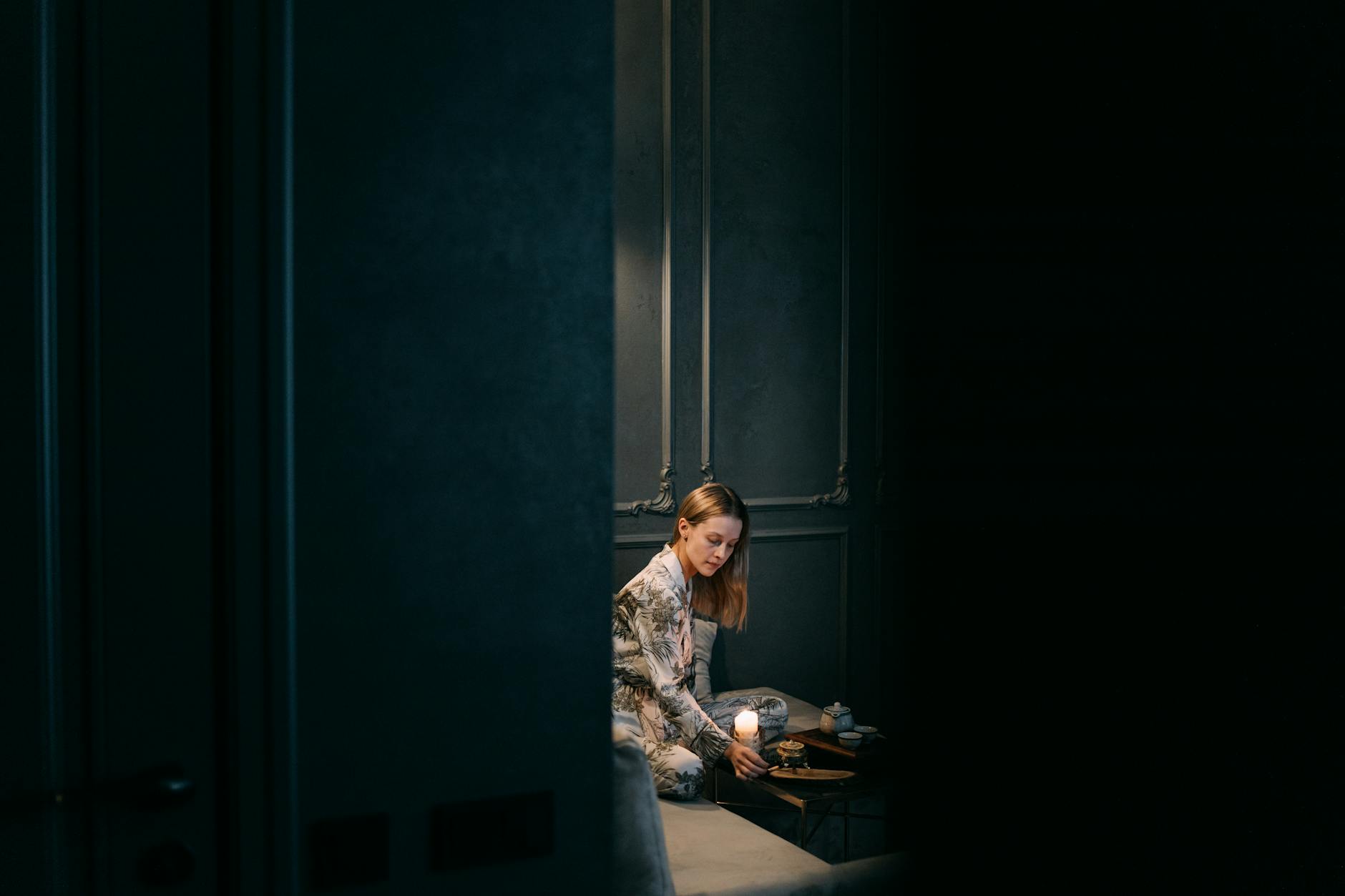 Kobieta odpoczywa przy herbacie w przyciemnionym, spokojnym wnętrzu