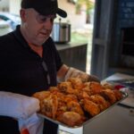 Mężczyzna trzyma blachę z pieczonym kurczakiem w rustykalnej kuchni