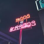 Neonowy napis Tacos vs Burritos na ulicy nocą