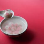 Różowa kluseczka w kształcie świnki w porcelanowej misce na czerwonym tle