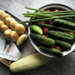 Świeże ogórki, pomidory i domowe bułki na rustykalnym drewnianym stole