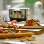 Talerz domowego makaronu z sosem pomidorowym na drewnianej desce w kuchni