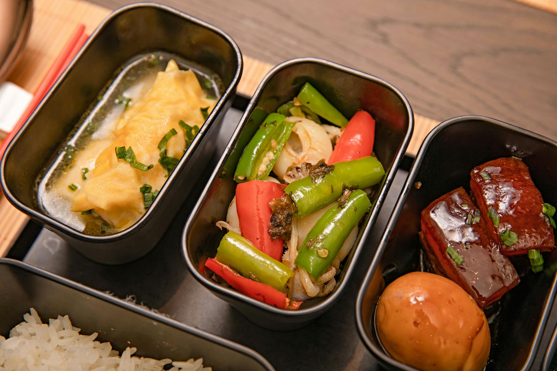 Zbliżenie na bento z pierożkami, warzywami i boczkiem