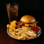 Zestaw fast food: cheeseburger z bekonem, frytki i nuggetsy z napojem