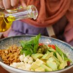 Zielona sałatka z awokado, jajkami przepiórczymi i orzechami polewana oliwą