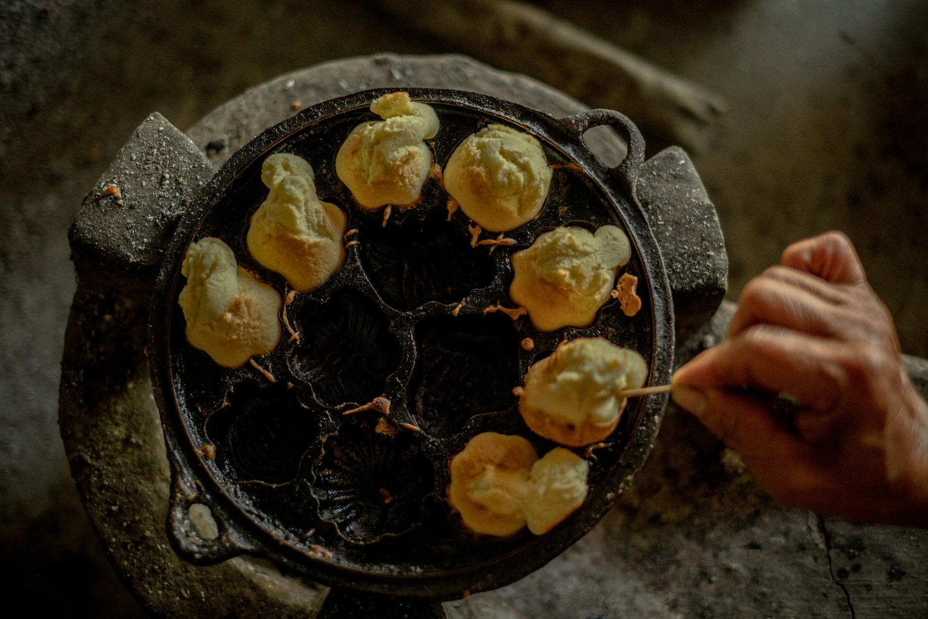 Dłoń smażąca tradycyjne wietnamskie placki na żeliwnej patelni