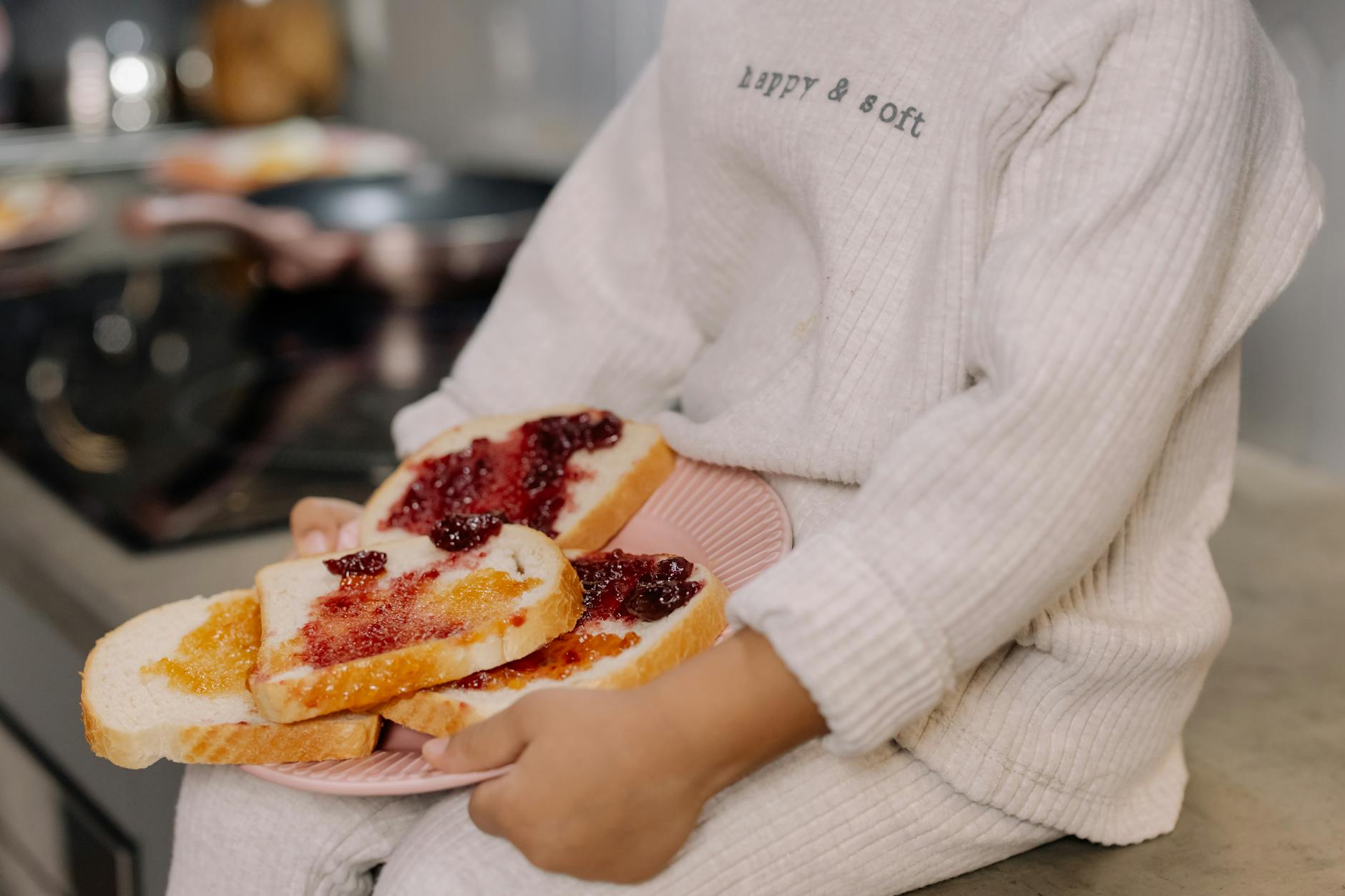 Dziecko w swetrze trzyma talerz słodkich kanapek na śniadanie Dziecko w swetrze trzyma talerz słodkich kanapek na śniadanie