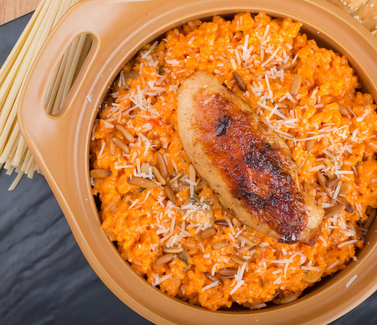 Kremowy makaron z grillowanym kurczakiem i tartym serem na talerzu